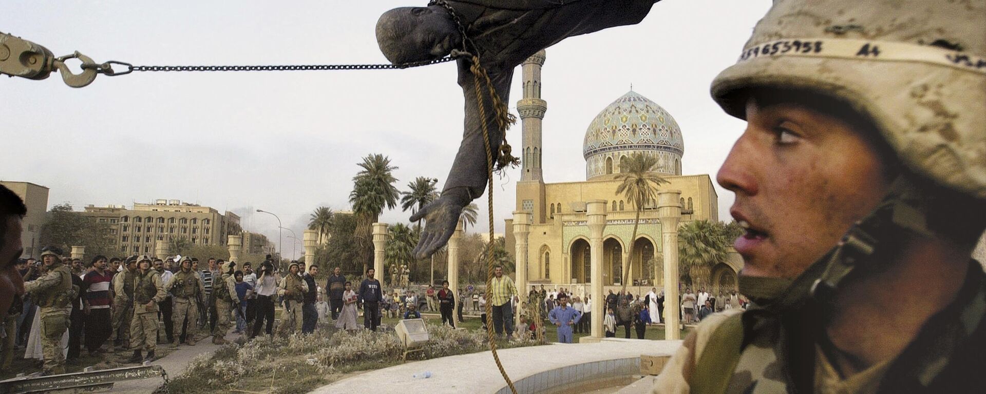 Civis iraquianos e soldados norte-americanos derrubam uma estátua de Saddam Hussein no centro de Bagdá, em 9 de abril de 2003 - Sputnik Brasil, 1920, 10.11.2023