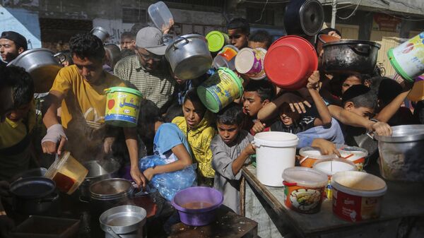 Palestinos durante distribuição de comida por agências internacionais que seguem no território em meio ao conflito com Israel. Faixa de Gaza, 8 de novembro de 2023 - Sputnik Brasil