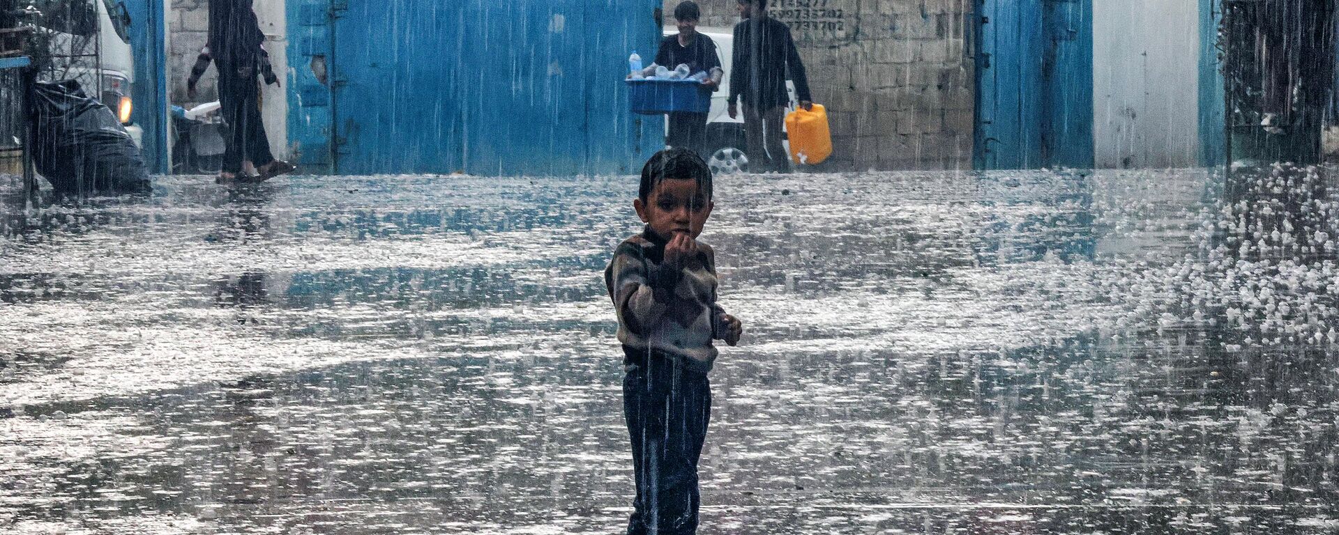 Um menino fica na chuva em uma escola administrada pela Agência das Nações Unidas de Assistência aos Refugiados da Palestina no Próximo Oriente (UNRWA, na sigla em inglês), em Rafah. Faixa de Gaza, 14 de novembro de 2023 - Sputnik Brasil, 1920, 23.11.2023