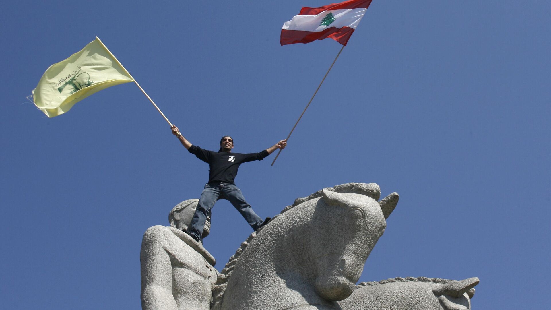 Manifestante segura a bandeira do Hezbollah do alto de um monumento em praça de São Paulo (SP). Brasil, 6 de agosto de 2006 - Sputnik Brasil, 1920, 23.11.2023