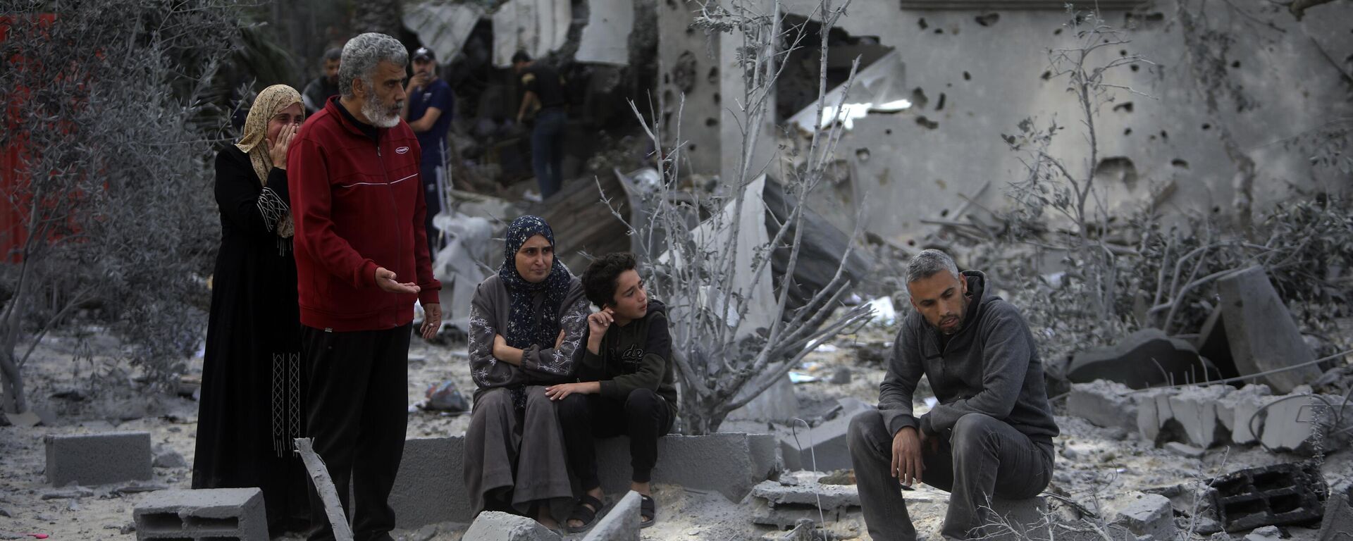 Palestinos se sentam sobre os escombros de uma casa destruída após ataques aéreos israelenses na cidade de Khan Yunis. Faixa de Gaza, 22 de novembro de 2023 - Sputnik Brasil, 1920, 23.11.2023