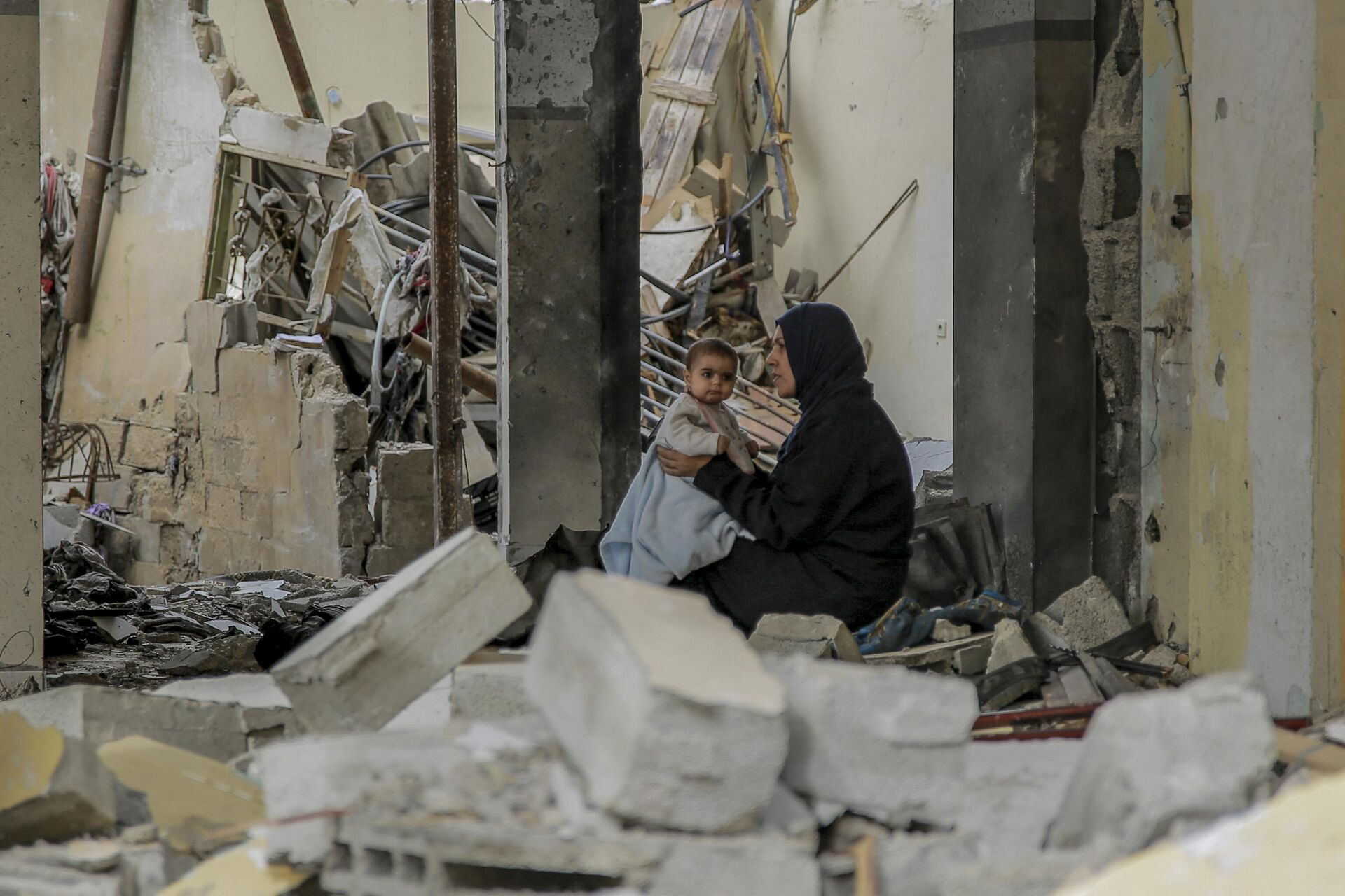 Uma mulher palestina segura seu bebê entre os escombros de edifícios destruídos na Cidade de Gaza, em 25 de novembro de 2023 - Sputnik Brasil, 1920, 25.11.2023