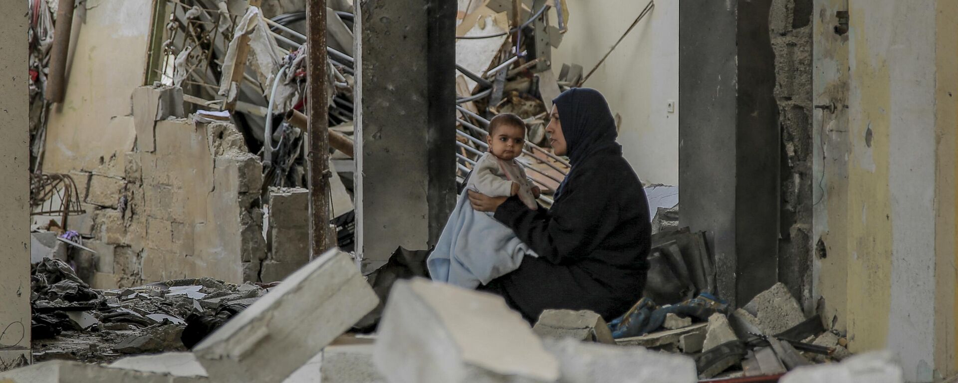 Uma mulher palestina segura seu bebê entre os escombros de edifícios destruídos na Cidade de Gaza, em 25 de novembro de 2023 - Sputnik Brasil, 1920, 02.03.2024