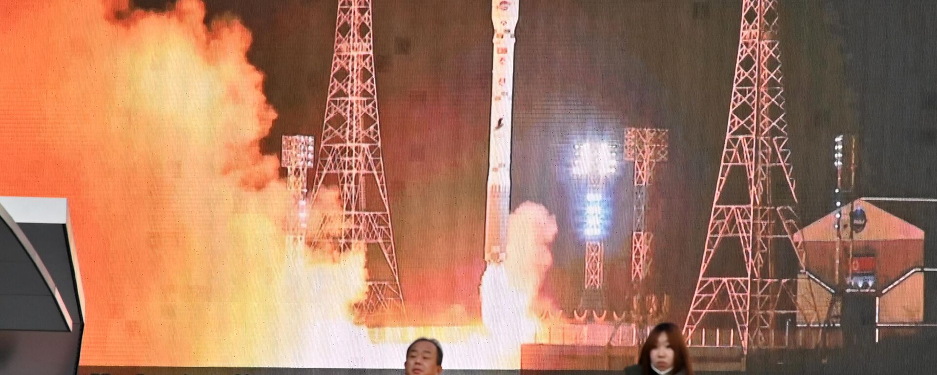 Pedestres passam por tela que exibe lançamento do Malligyong-1, um satélite de reconhecimento da Coreia do Norte, em Tóquio, Japão, 22 de novembro de 2023 - Sputnik Brasil, 1920, 26.11.2023