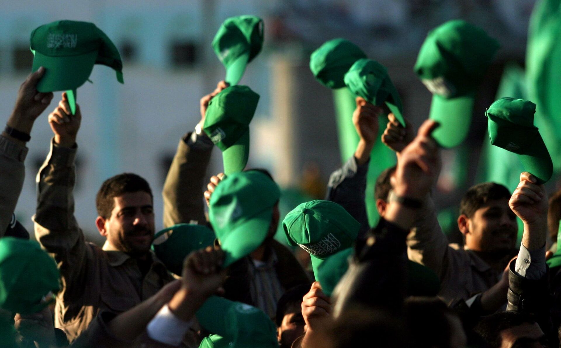 Os apoiadores palestinos do Hamas erguem seus chapéus verdes durante uma manifestação celebrando a vitória do grupo nas eleições parlamentares, no Campo de Refugiados Khan Younis, no sul da Faixa de Gaza, em 27 de janeiro de 2006 - Sputnik Brasil, 1920, 29.11.2023