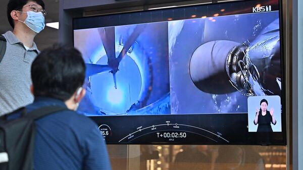 Pessoas assistem a uma tela de televisão mostrando uma filmagem ao vivo de um foguete SpaceX Falcon 9 sendo lançado com o primeiro orbitador lunar da Coreia do Sul, Danuri, a bordo do Cabo Canaveral, na Flórida, em uma estação ferroviária em Seul, em 5 de agosto de 2022 - Sputnik Brasil