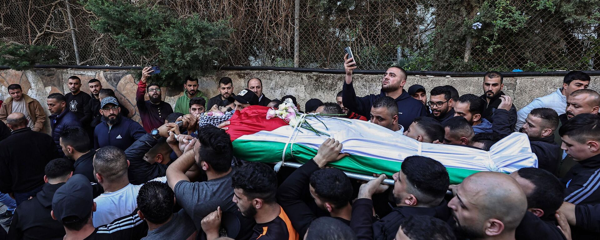 Palestinos carregam corpo de homem morto durante confrontos com as forças israelenses no campo de Qalandia, durante cortejo fúnebre fora do hospital do governo de Ramallah, Cisjordânia, 4 de dezembro de 2023 - Sputnik Brasil, 1920, 09.02.2024