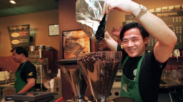 Funcionário despeja grãos de café em moedor na abertura da primeira loja de café da marca americana Starbucks na China, em 11 de janeiro de 1999 - Sputnik Brasil