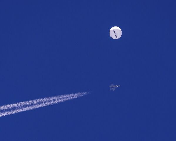 Um caça voa perto de um grande balão à deriva sobre o oceano Atlântico. Minutos depois, o balão foi atingido por um míssil de um caça F-22, encerrando sua travessia de uma semana sobre os EUA,  Montana, EUA, 4 de fevereiro de 2023. - Sputnik Brasil