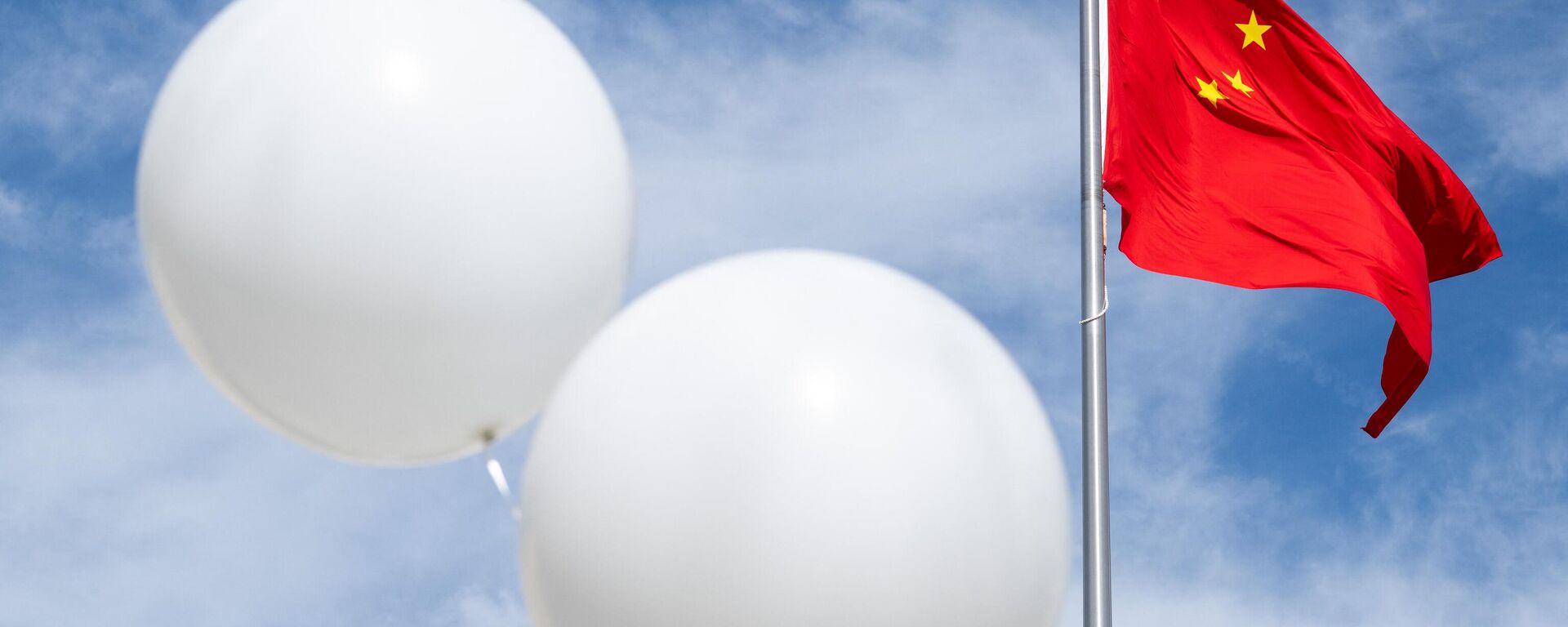 Dois balões brancos flutuam perto da bandeira chinesa enquanto o ativista Rev. Patrick Mahoney protesta contra o governo chinês sobre o suposto balão de vigilância chinês que foi abatido sobre os EUA na semana passada, durante uma manifestação do lado de fora da Embaixada da China em Washington, DC, 15 de fevereiro de 202 - Sputnik Brasil, 1920, 18.12.2023