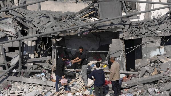 Palestinos tentam salvar objetos pessoais em meio a destroços de prédio atingido por ataque israelense. Faixa de Gaza, 18 de dezembro de 2023 - Sputnik Brasil