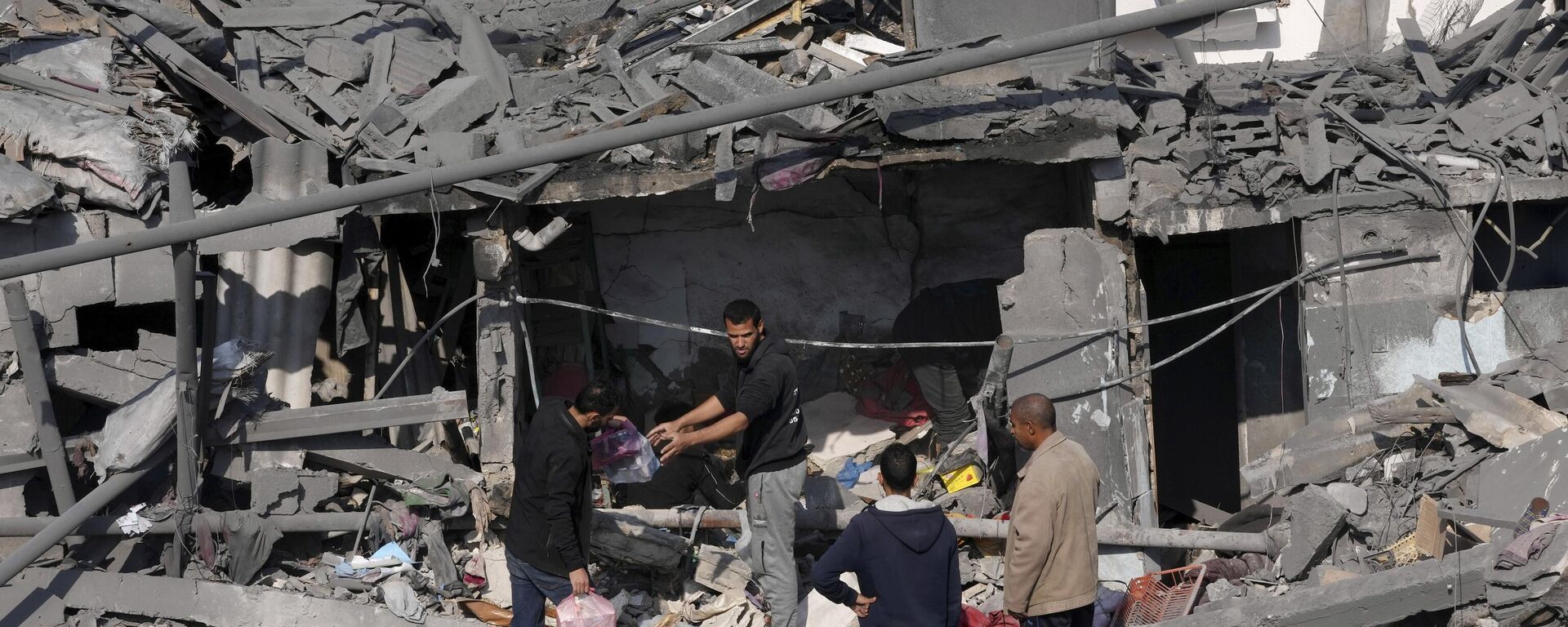 Palestinos tentam salvar objetos pessoais em meio a destroços de prédio atingido por ataque israelense. Faixa de Gaza, 18 de dezembro de 2023 - Sputnik Brasil, 1920, 18.12.2023