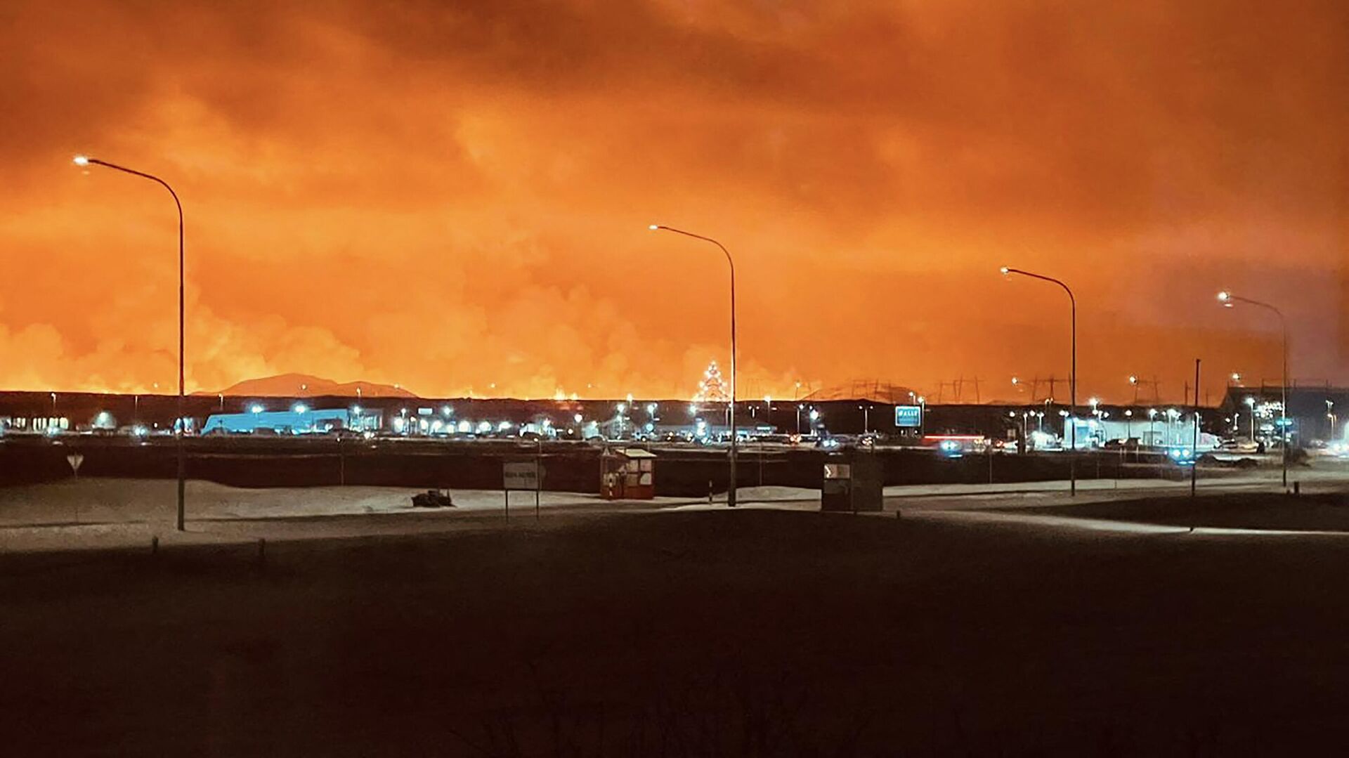 Ruas na cidade de Keflavik são mostradas como fumaça que se espalha com a cor da lava colorindo o céu noturno de laranja devido a uma erupção vulcânica na península de Reykjanes, no oeste da Islândia, em 18 de dezembro de 2023.  - Sputnik Brasil, 1920, 19.12.2023