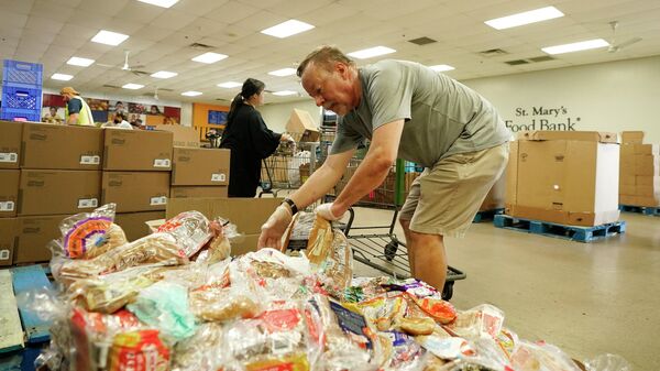 Voluntários enchem carrinhos de supermercado com alimentos para distribuição em veículos no drive through no Banco de Alimentos do St. Mary, em Phoenix, 29 de junho de 2022 - Sputnik Brasil