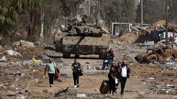 Palestinos que fogem do norte pela estrada Salaheddine, no distrito de Zeitoun, na periferia sul da cidade de Gaza, passam por tanques do Exército israelense em 24 de novembro de 2023 - Sputnik Brasil