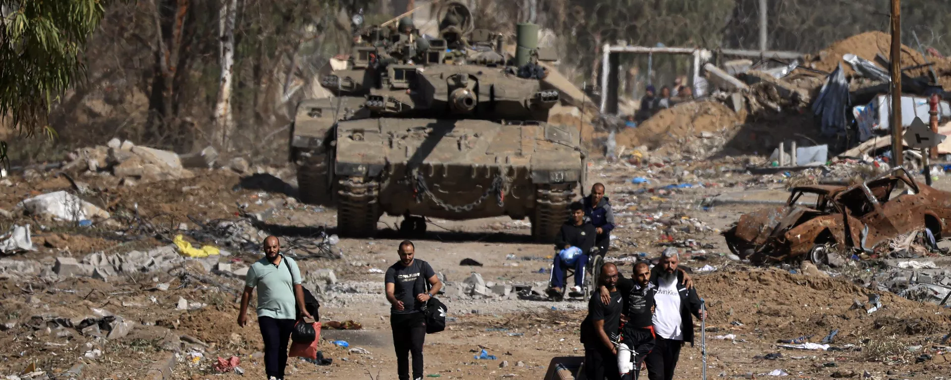 Palestinos que fogem do norte pela estrada Salaheddine, no distrito de Zeitoun, na periferia sul da cidade de Gaza, passam por tanques do Exército israelense em 24 de novembro de 2023 - Sputnik Brasil, 1920, 21.12.2023