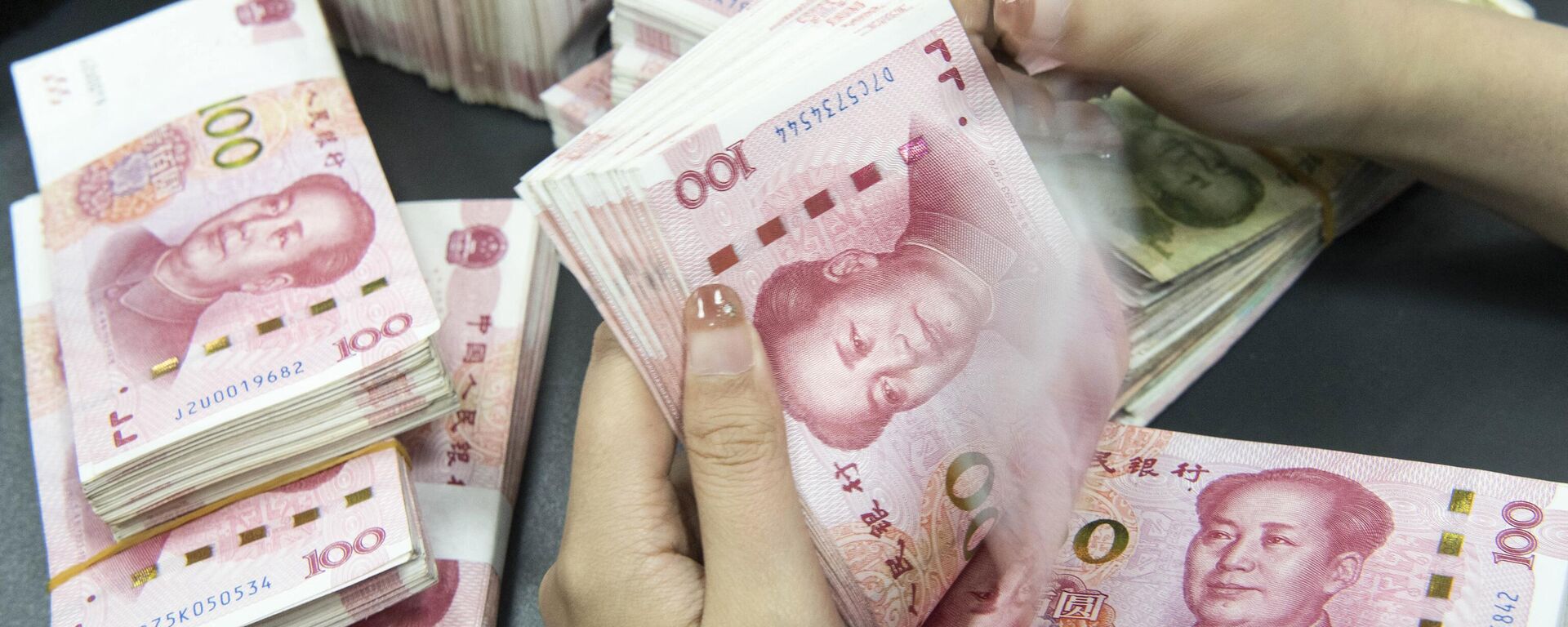 Um funcionário de um banco contando notas de 100 yuans em um balcão de banco em Nantong, na província de Jiangsu, no leste da China, 13 de novembro de 2023 - Sputnik Brasil, 1920, 23.12.2023