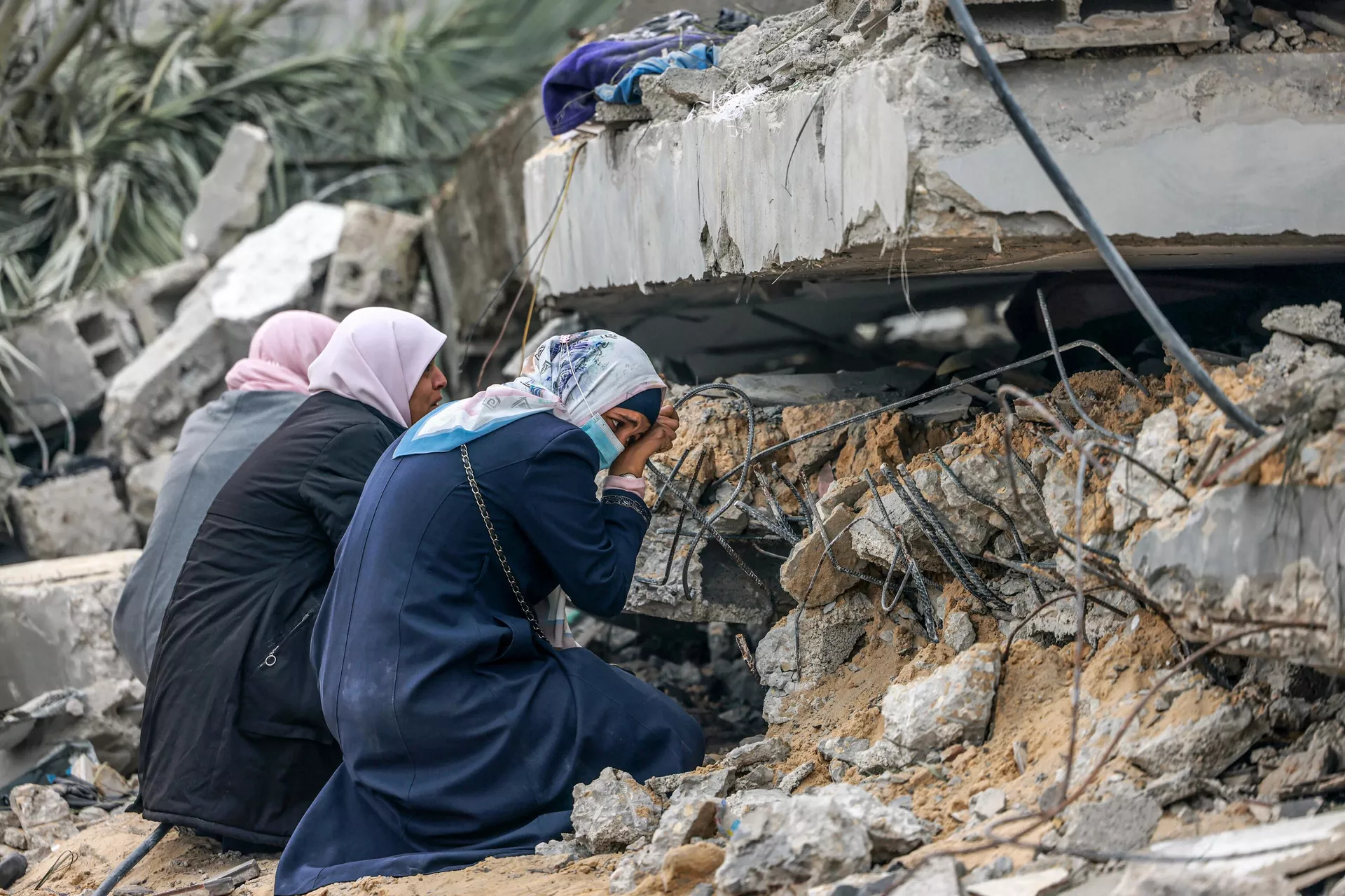 Mulheres palestinas choram onde se acredita que um parente esteja preso nos escombros após o bombardeio israelense em Rafah, no sul da Faixa de Gaza, em 21 de dezembro de 2023 - Sputnik Brasil, 1920, 11.01.2024