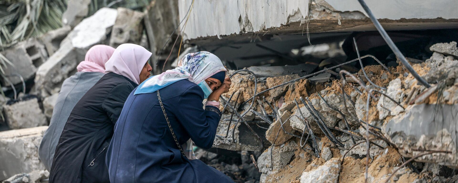 Mulheres palestinas choram onde se acredita que um parente esteja preso nos escombros após o bombardeio israelense em Rafah, no sul da Faixa de Gaza, em 21 de dezembro de 2023 - Sputnik Brasil, 1920, 15.01.2024