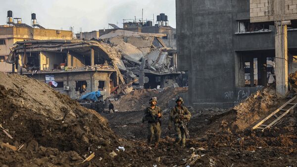 Soldados israelenses passando por edifícios danificados durante uma operação militar no norte da Faixa de Gaza, 19 de dezembro de 2023 - Sputnik Brasil