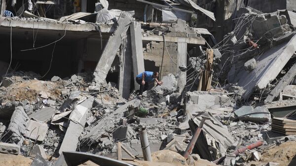 Palestino sai de prédio destruído por bombardeio israelense na Faixa de Gaza, no campo de refugiados Al-Maghazi, em Deir al-Balah, em 25 de outubro de 2023 - Sputnik Brasil