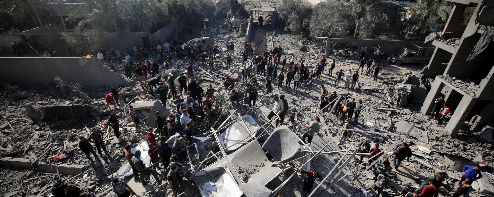 Palestinos procuram sobreviventes em escombros de edifícios após ataques israelenses no campo de refugiados de al-Maghazi, em meio a batalhas contínuas entre Israel e o movimento palestino Hamas no centro da Faixa de Gaza, em 11 de dezembro de 2023 - Sputnik Brasil, 1920, 25.12.2023