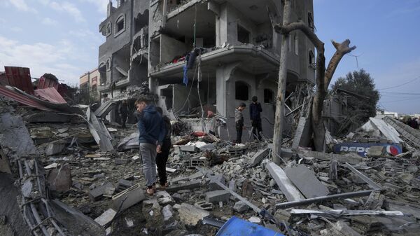 Famílias em meio aos destroços após bombardeios intensos das Forças de Defesa de Israel contra o campo de refugiados em Maghazi. Faixa de Gaza, 25 de dezembro de 2023 - Sputnik Brasil