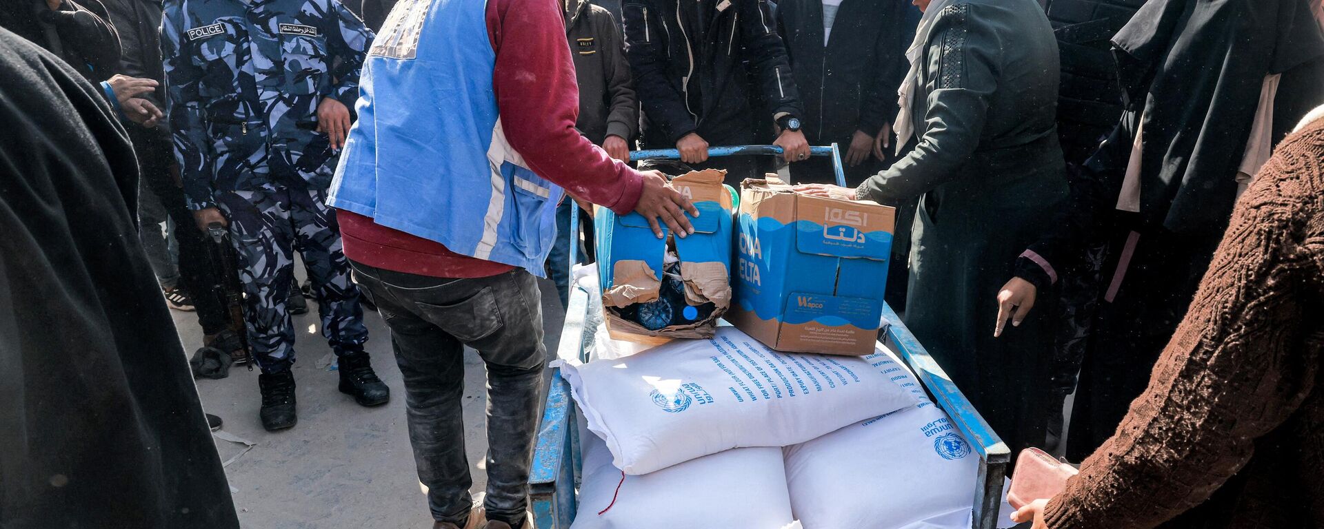 Trabalhadores da Agência das Nações Unidas de Assistência e Obras aos Refugiados da Palestina (UNRWA) distribuem rações de farinha e outros suprimentos às pessoas em um armazém da UNRWA em Rafah, no sul da Faixa de Gaza, em 12 de dezembro de 2023 - Sputnik Brasil, 1920, 30.12.2023
