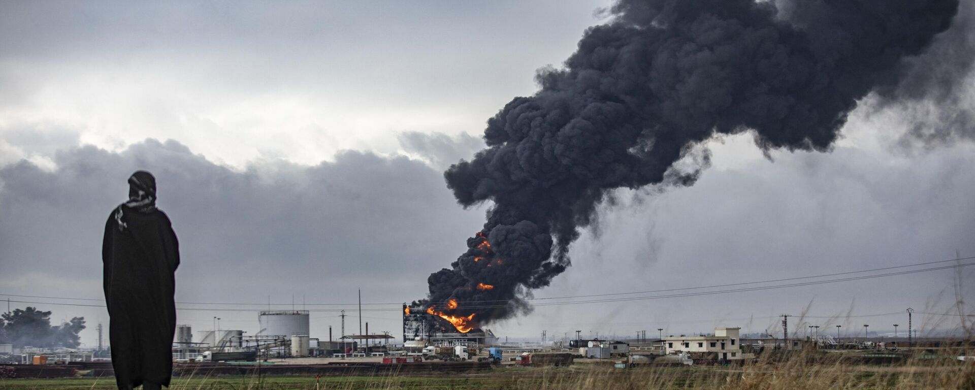 A fumaça espessa surge de um incêndio violento em um tanque de armazenamento das instalações do campo de petróleo de al-Awda, perto de al-Qahtaniyah, no nordeste da Síria, perto da fronteira com a Turquia, em 24 de dezembro de 2023 - Sputnik Brasil, 1920, 31.12.2023