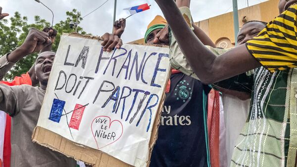 Manifestantes seguram um cartaz anti-França durante uma manifestação no dia da independência em Niamey, em 3 de agosto de 2023. Preocupações de segurança construídas em 3 de agosto de 2023 - Sputnik Brasil