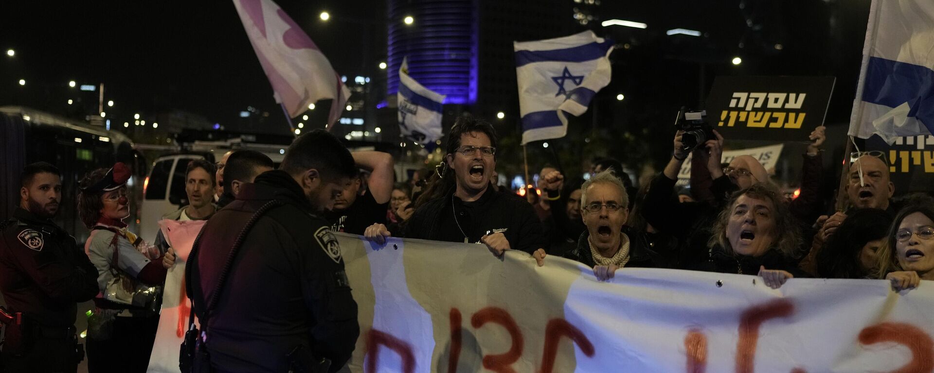 Manifestantes bloqueiam uma rua próxima à Praça dos Reféns, exibindo cartazes contra o governo enquanto exigem a libertação dos reféns levados por militantes do Hamas à Faixa de Gaza, em Tel Aviv, Israel, no sábado, 13 de janeiro de 2024 - Sputnik Brasil, 1920, 13.01.2024
