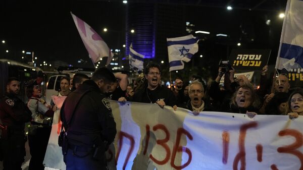 Manifestantes bloqueiam uma rua próxima à Praça dos Reféns, exibindo cartazes contra o governo enquanto exigem a libertação dos reféns levados por militantes do Hamas à Faixa de Gaza, em Tel Aviv, Israel, no sábado, 13 de janeiro de 2024 - Sputnik Brasil