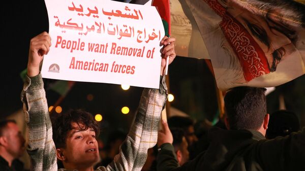 Homem levanta cartaz durante um protesto contra os ataques das forças dos EUA e do Reino Unido contra os rebeldes houthis do Iêmen e contra a presença das forças dos Estados Unidos no Iraque, na praça Tahrir, em Bagdá, Iraque, 13 de janeiro de 2024 - Sputnik Brasil