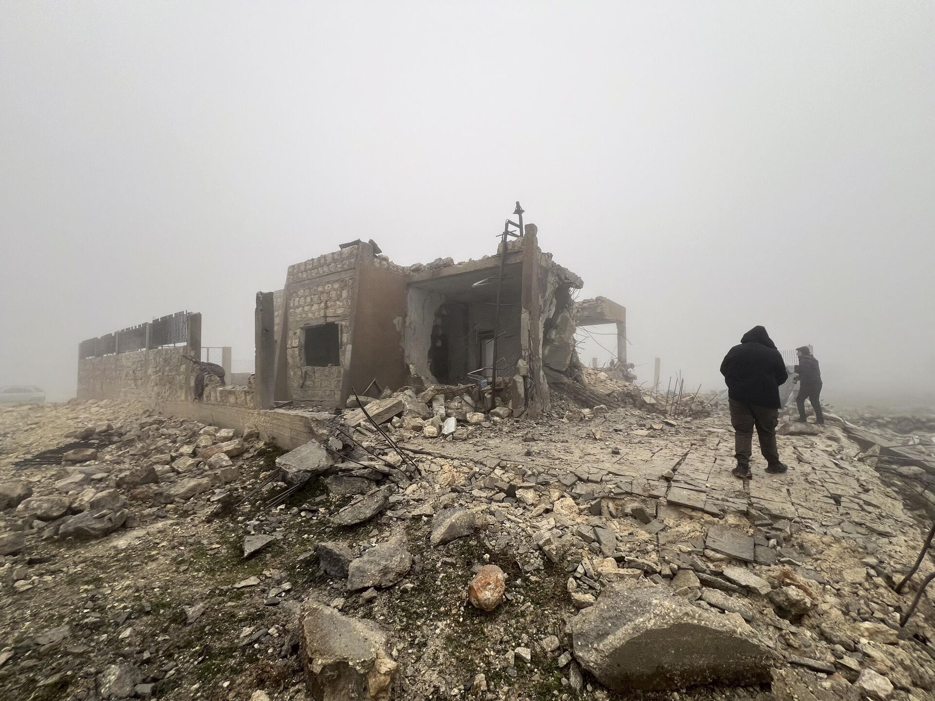 Sírios olham para um centro médico abandonado na vila de Talteta que foi atingido por mísseis iranianos na noite de segunda-feira (15), Síria, 16 de janeiro de 2024 - Sputnik Brasil, 1920, 16.01.2024