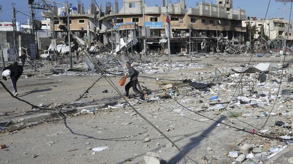 Palestinos passam pela destruição causada por um bombardeio israelense no campo de refugiados de Nusseirat. Faixa de Gaza, 16 de janeiro de 2024 - Sputnik Brasil