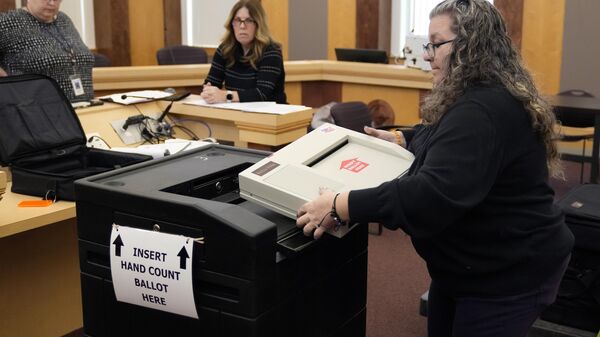 Lisa Hultgren (D), a moderadora da cidade de Derry, New Hampshire, carrega uma máquina de contagem de votos em um carrinho, que armazena as cédulas de papel, enquanto testa as máquinas de contagem de votos antes das primárias de New Hampshire no Centro Municipal de Derry, 16 de janeiro de 2024 - Sputnik Brasil