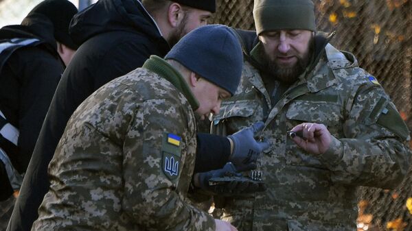 A polícia ucraniana e especialistas militares coletam fragmentos de um drone russo abatido em um pátio entre edifícios residenciais em Kiev, em 25 de novembro de 2023 - Sputnik Brasil