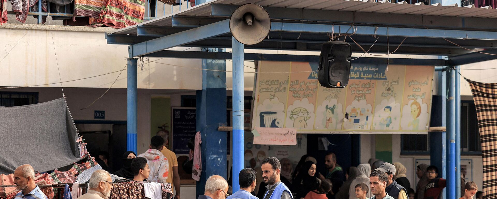 Pessoas caminham no parquinho de uma escola administrada pela Agência das Nações Unidas de Assistência e Obras para os Refugiados da Palestina (UNRWA), que foi convertida em um abrigo para palestinos deslocados em Khan Yunis, no sul da Faixa de Gaza, em 25 de outubro de 2023 - Sputnik Brasil, 1920, 04.02.2024