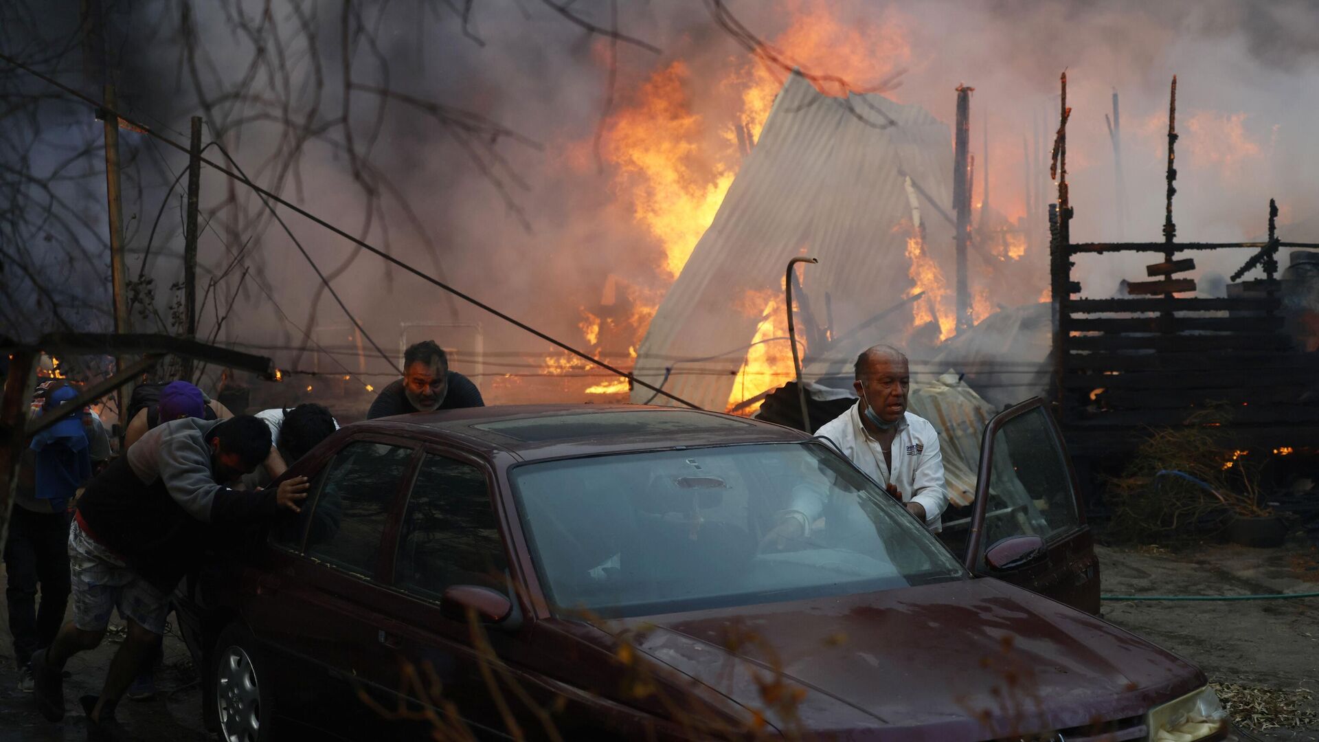 Moradores empurram um carro para longe das chamas que envolvem casas em Villa Alemana, em Valparaíso. Chile, 2 de fevereiro de 2024 - Sputnik Brasil, 1920, 04.02.2024