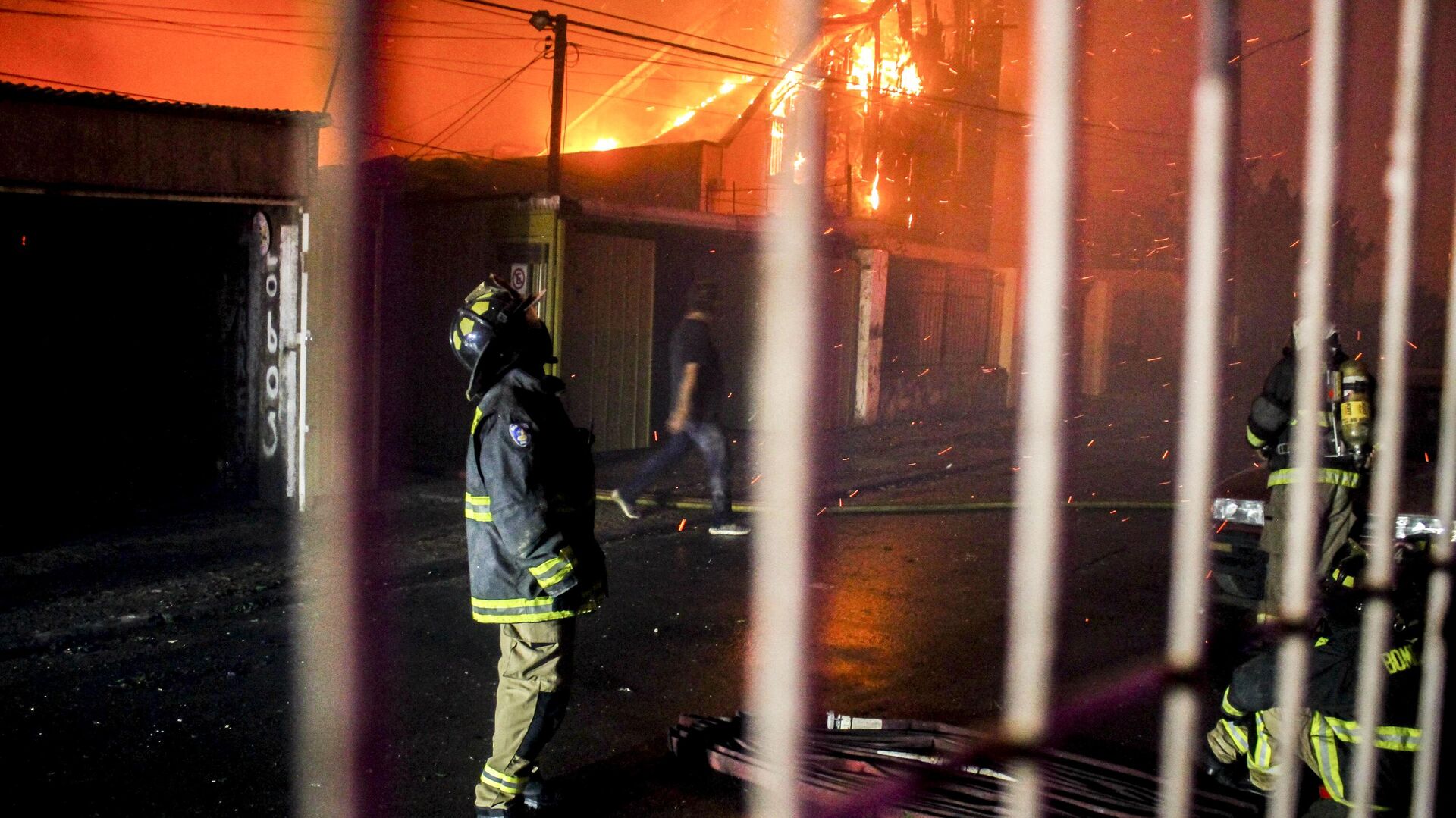 Um bombeiro olha para cima enquanto as chamas espalhadas por um incêndio florestal envolvem edifícios em Vina del Mar. Chile, 2 de fevereiro de 2024 - Sputnik Brasil, 1920, 04.02.2024