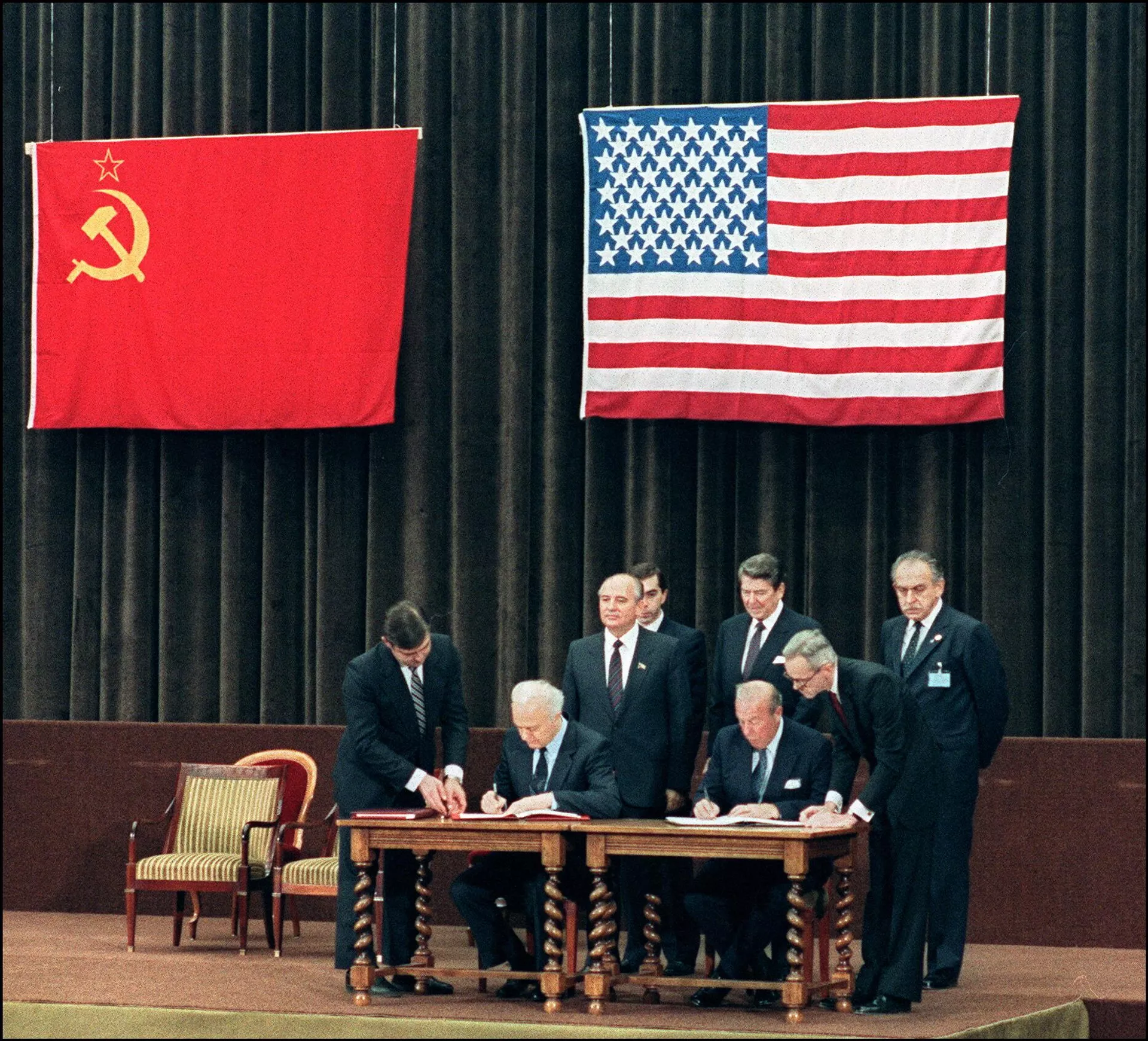 O então presidente dos EUA, Ronald Reagan (atrás do homem sentado à direita), e o então secretário-geral do Partido Comunista da União Soviética, Mikhail Gorbachev (ao lado de Reagan), na assinatura de uma declaração comum no final da cúpula de dois dias entre as superpotências, em 21 de novembro de 1985 - Sputnik Brasil, 1920, 06.02.2024