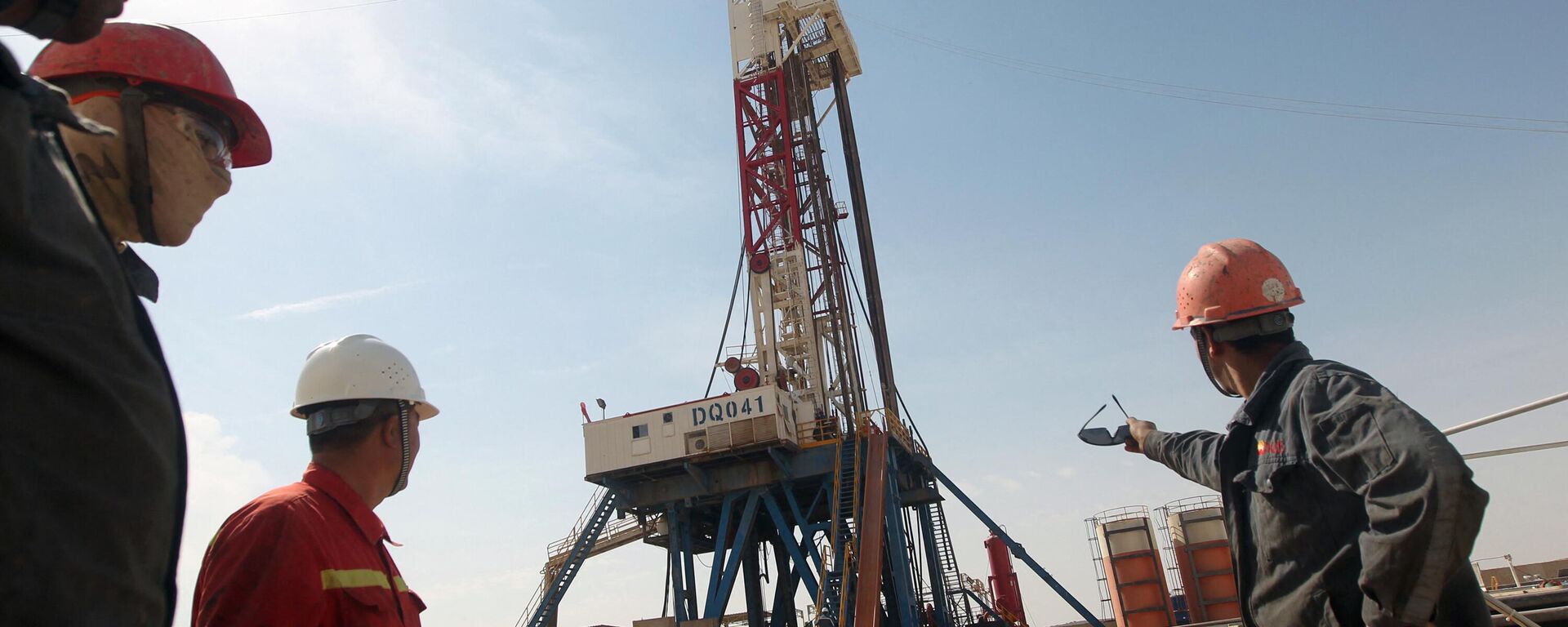 Funcionários da Gazprom observam uma plataforma de perfuração da empresa Gazprom em um campo petrolífero perto da cidade iraquiana de Badra, ao sul de Bagdá, em 18 de outubro de 2012 - Sputnik Brasil, 1920, 07.02.2024