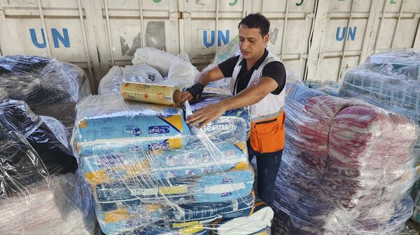 Trabalhadores das Nações Unidas e do Crescente Vermelho preparam a ajuda para distribuição aos palestinos no armazém da UNRWA em Deir Al-Balah, Faixa de Gaza, 23 de outubro de 2023 - Sputnik Brasil