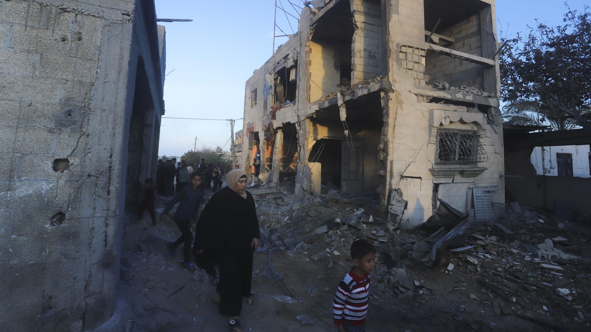 Palestinos passam por prédio residencial destruído em um ataque israelense em Rafah. Faixa de Gaza, 11 de fevereiro de 2024 - Sputnik Brasil, 1920, 12.02.2024