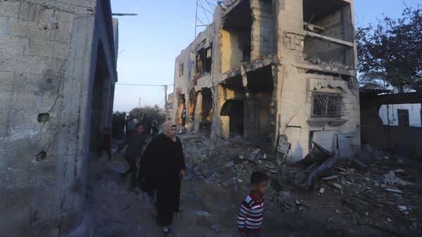 Palestinos passam por prédio residencial destruído em um ataque israelense em Rafah. Faixa de Gaza, 11 de fevereiro de 2024 - Sputnik Brasil