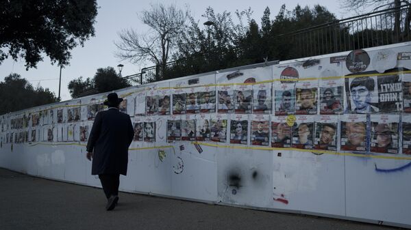 Homem observa mural com retratos de israelenses que foram sequestrados durante o ataque sem precedentes do Hamas contra Israel, em 7 de outubro de 2023. Jerusalém, 30 de janeiro de 2024 - Sputnik Brasil