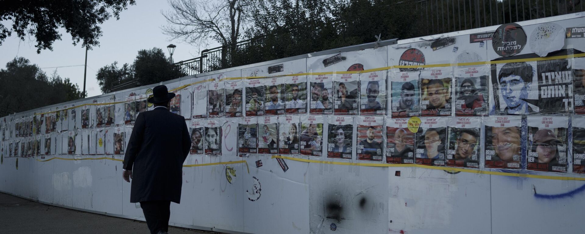 Homem observa mural com retratos de israelenses que foram sequestrados durante o ataque sem precedentes do Hamas contra Israel, em 7 de outubro de 2023. Jerusalém, 30 de janeiro de 2024 - Sputnik Brasil, 1920, 12.02.2024