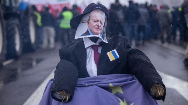 Um manequim feito de palha com o rosto do comissário agrícola da UE, Janusz Wojciechowski, sentado em uma cadeira de rodas coberta com a bandeira da UE, enquanto agricultores bloqueiam o acesso à passagem da fronteira entre a Polônia e a Ucrânia em Dorohusk, leste da Polônia, em 9 de fevereiro de 2024 - Sputnik Brasil
