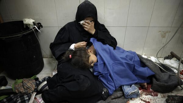 Palestina ao lado da filha ferida após bombardeio israelense no Hospital Nasser, no sul da Faixa de Gaza. Khan Younis, 22 de janeiro de 2024 - Sputnik Brasil