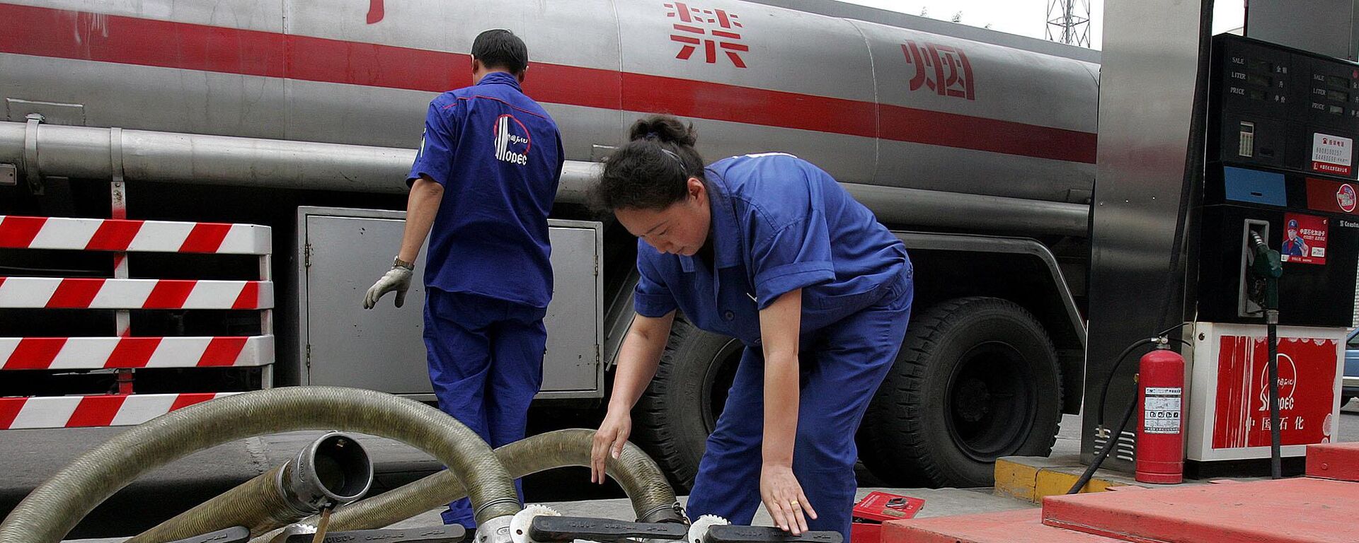 Trabalhador chinês de uma das maiores empresas de petróleo da China, a Sinopec, manuseia mangueiras após entregar gasolina em um posto em Pequim, China. - Sputnik Brasil, 1920, 02.03.2024
